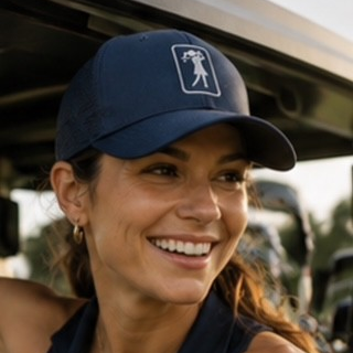 Woman smiling in a golf cart wearing the Platinum hat at golden hour