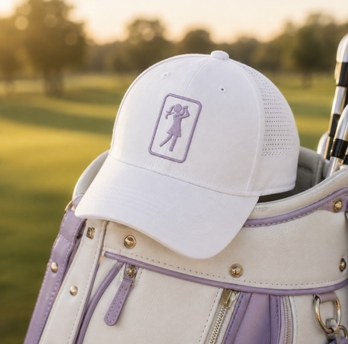 Heather golf hat resting on a white and lavender golf bag on the course at golden hour